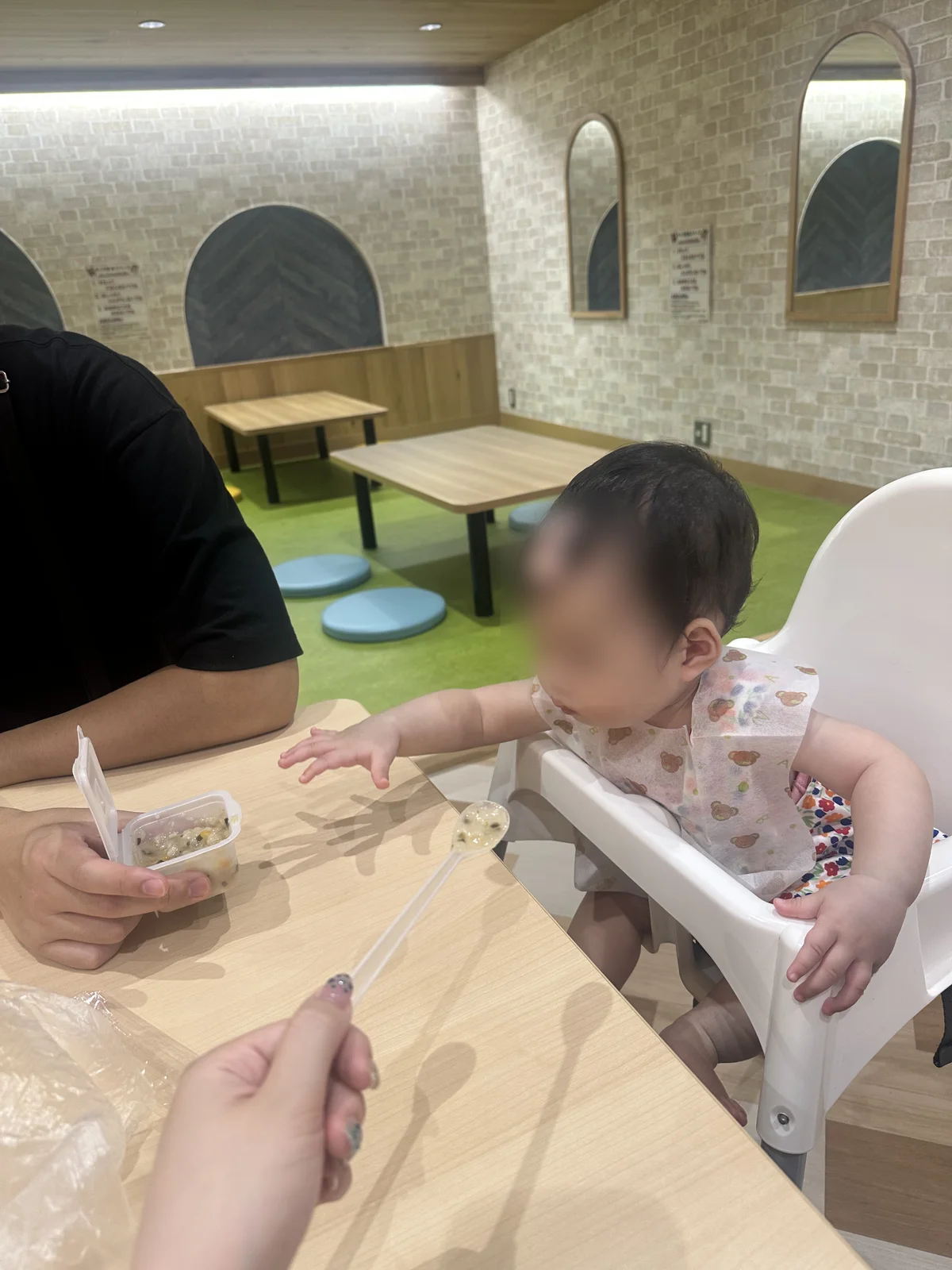 キッズ飲食スペースのベビーチェアで離乳食を食べる赤ちゃん